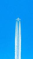 Four engined airplane during flight in high altitude with condensation trails photo