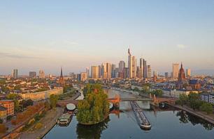 imagen aérea del horizonte de frankfurt y el río principal durante el amanecer con reflejos en el agua y las fachadas de vidrio de los rascacielos foto