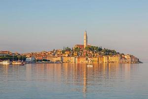 silueta de la histórica ciudad de rovinj a la hora de la mañana con reflejos de luz en el agua foto