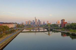 imagen aérea del horizonte de frankfurt y el río principal durante el amanecer con reflejos en el agua y las fachadas de vidrio de los rascacielos foto