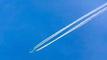 Four engined airplane during flight in high altitude with condensation trails photo