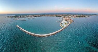 Drone panorama of the Croatian coastal town Umag taken during sunset above the harbor entrance with breakwater photo