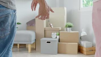 Moving house, relocation. Couple hold key house keychain in new apartment, inside the room was a cardboard box containing personal belongings and furniture. move in the new apartment or condominium video