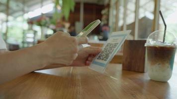 kvinna använda sig av smartphone till skanna qr koda till betala i Kafé restaurang med en digital betalning utan kontanter. välja meny och beställa ackumulera rabatt. e plånbok, teknologi, betala uppkopplad, kreditera kort, Bank app. video