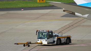 DUSSELDORF, GERMANY JULY 23, 2017 - A tow tractor pulls up to the plane at the airport. Airport traffic video