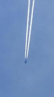 Two engined airplane during flight in high altitude with condensation trails photo