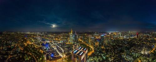 panorama aéreo de drones del horizonte de frankfurt por la noche con luna llena y rascacielos iluminados foto