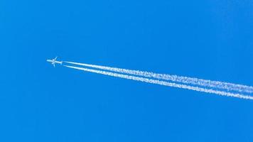 Two engined airplane during flight in high altitude with condensation trails photo