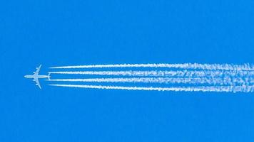 Four engined airplane during flight in high altitude with condensation trails photo