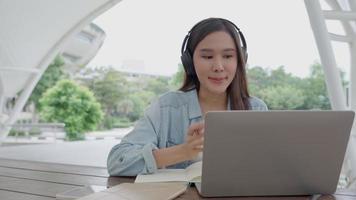 Beautiful Asian woman female student excited checking language test results on laptop. Smile girl happy study online. book in college campus. Portrait female on international Asia University video