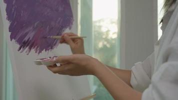 une artiste professionnelle utilise un pinceau dans l'art abstrait pour créer un chef-d'œuvre. peinture de peintre à l'aquarelle ou à l'huile dans la maison de studio. belle femme aime peindre comme passe-temps. travail loisirs