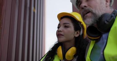 Handheld panning shot, middle-aged Caucasian business engineer man and pretty secretary female checking transport container, They are talking and write into report paper on clipboard at storage video