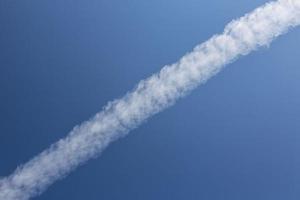 Condensation trail of an airplane in blue sky photo