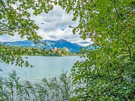 View of Bled castle and pilgrimage church with the Alps in the background in Slovenia during the day photo