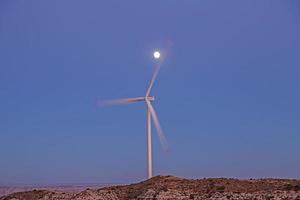 Image of rotating wind turbine in evening light with full moon photo