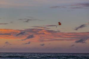 imagen de un parapente al atardecer desde la playa de kamala en tailandia en verano foto