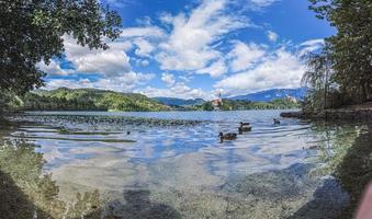 View of Bled castle and pilgrimage church with the Alps in the background in Slovenia during the day photo