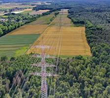 Aerial view along a power line in forest area with metal power poles and high voltage wires photo