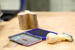 sello de goma de madera de primer plano con placa de tinta azul en la mesa de la oficina y fondo borroso. foto