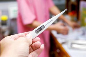 Closeup Medical thermometer in hands of doctor on blurry background.. photo