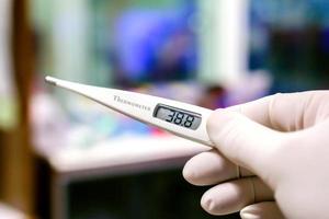Closeup Medical thermometer in hands of doctor on blurry background.. photo
