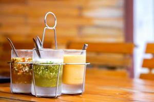salsa de estilo tailandés en vidrio con soporte de condimento de base de vidrio sobre mesa de madera foto