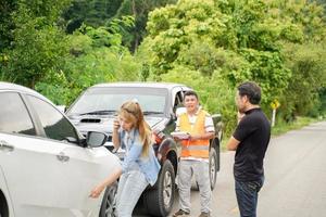 Drivers stood arguing after the car crashed with insurance company officer checking car damages on country road. photo