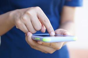 Asian woman's hand is poking at the phone screen. photo