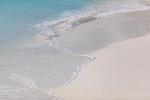 Beach background with sandy beautiful white foamy and wave from the sea, beach top view. Peaceful beach nature, photo