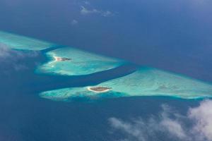 Aerial view of Maldives resort, luxury travel destination. Birds eye view of deep blue sea, coral reed, tropical island. Amazing nature view, drone aerial landscape photo