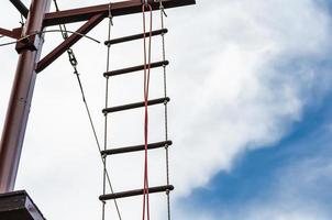 escalera de cuerda contra un cielo azul y nubes foto