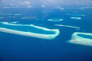 Aerial view of Maldives resort, luxury travel destination. Birds eye view of deep blue sea, coral reed, tropical island. Amazing nature view, drone aerial landscape photo