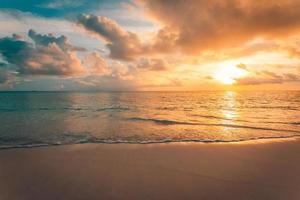 Closeup of sea beach and colorful sunset sky. Panoramic beach landscape. Empty tropical beach and seascape. Orange and golden sunset sky, soft sand, calmness, tranquil relaxing sunlight, summer mood