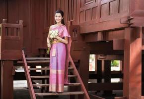 Thai girl dresses Thai traditional costume at traditional Thai house photo