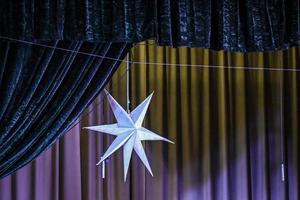 una elegante estrella brillante colgando de la cortina oscura en el escenario foto