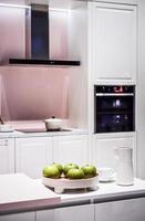 A detail of a modern white kitchen with some green apples in a bowl photo