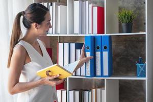 Asian businesswoman presenting business data with a board with charts, graphs hand holding a yellow notebook, And business documents lying on the table in the office, business concept. photo