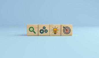 Concept of business strategy and action plan. Wooden cube block with icon target, light bulb and search on blue background. photo