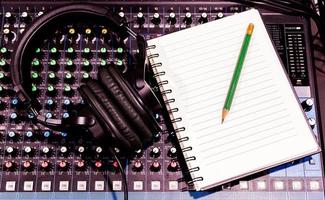 Top view black headphone and notebook on console sound board mixer photo