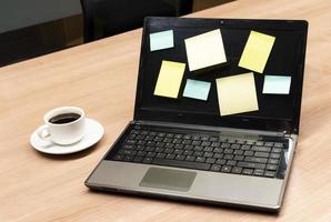 Colorful memo sticker on display laptop with black coffee cup on table photo