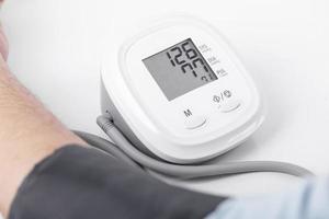 el hombre de negocios verifica la presión arterial y la frecuencia cardíaca con un manómetro sobre fondo blanco, salud y concepto médico foto