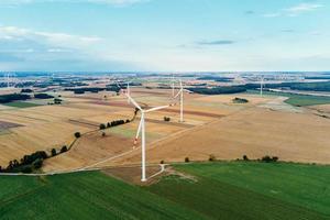 Windmill among agricultural fields. Wind turbine generator at summer day photo