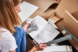 Woman reading manual instruction to assemble furniture photo