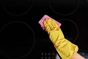 Woman in rubber gloves cleaning induction stove photo