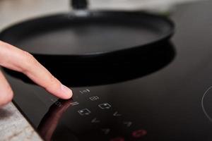 Woman hand turns on modern induction stove in the kitchen photo