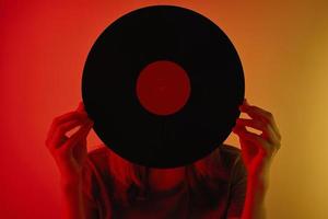 Woman covered her face with retro vinyl disc, toned photo
