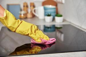 Woman in rubber gloves cleaning induction stove photo