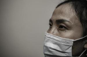 Tired depressed female asian scrub nurse wears face mask blue uniform sits on hospital floor,Young woman doctor stressed from hard work photo