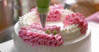 Close-up top view The chef is squeezing the cream into the green dot on top of the cake. video