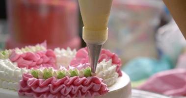 vue de face le chef presse la crème pour faire une guirlande sur le dessus du gâteau de la fête des mères.